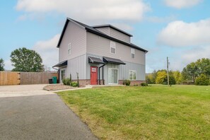 Una casa a due piani con una porta rossa, un portico coperto e un prato curato.
