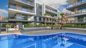 A modern building with a swimming pool, balconies, and palm trees. - Modern and comfortable apartment in Javea, Costa Blanca, Spain  with communal pool for 6 persons (Javea)