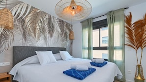A modern hotel room with a large bed, white bedding, a grey headboard, and a large window with green curtains. - Modern and comfortable apartment in Javea, Costa Blanca, Spain  with communal pool for 6 persons (Javea)