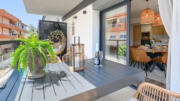 A balcony with a dining table, chairs, a potted plant, and a bottle of champagne. - Modern and comfortable apartment in Javea, Costa Blanca, Spain  with communal pool for 6 persons (Javea)