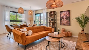 A modern living room with a sofa, dining table, and hanging wicker lamps. - Modern and comfortable apartment in Javea, Costa Blanca, Spain  with communal pool for 6 persons (Javea)