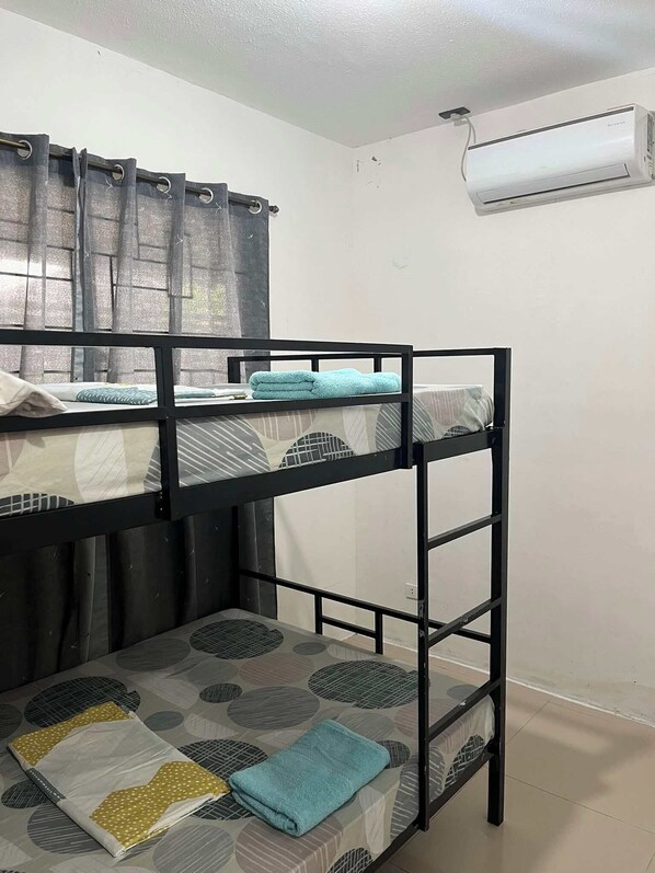 Habitación con literas, ventana, cortinas y aire acondicionado.