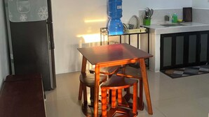 A modern kitchen with a dining table, chairs, a refrigerator, and a water dispenser.