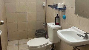 A small bathroom with a toilet, sink, and shower.