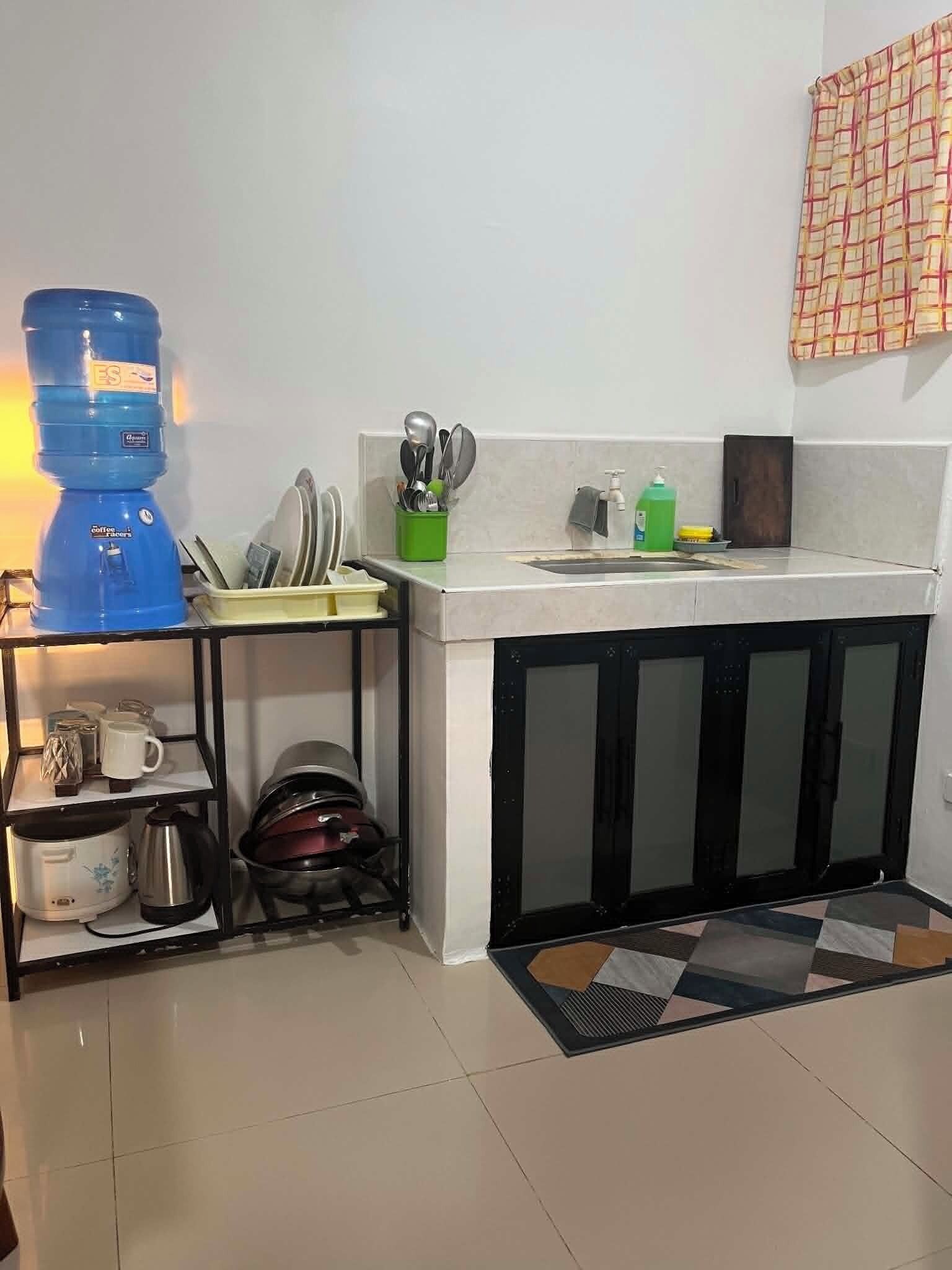A kitchen with a water dispenser, a coffee machine, and a sink.