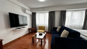 A living room with a flat-screen TV, a sofa, a coffee table, and a chair. -  Aparts4Days 1 Bedroom Apartment San Isidro Olivar (Lima)