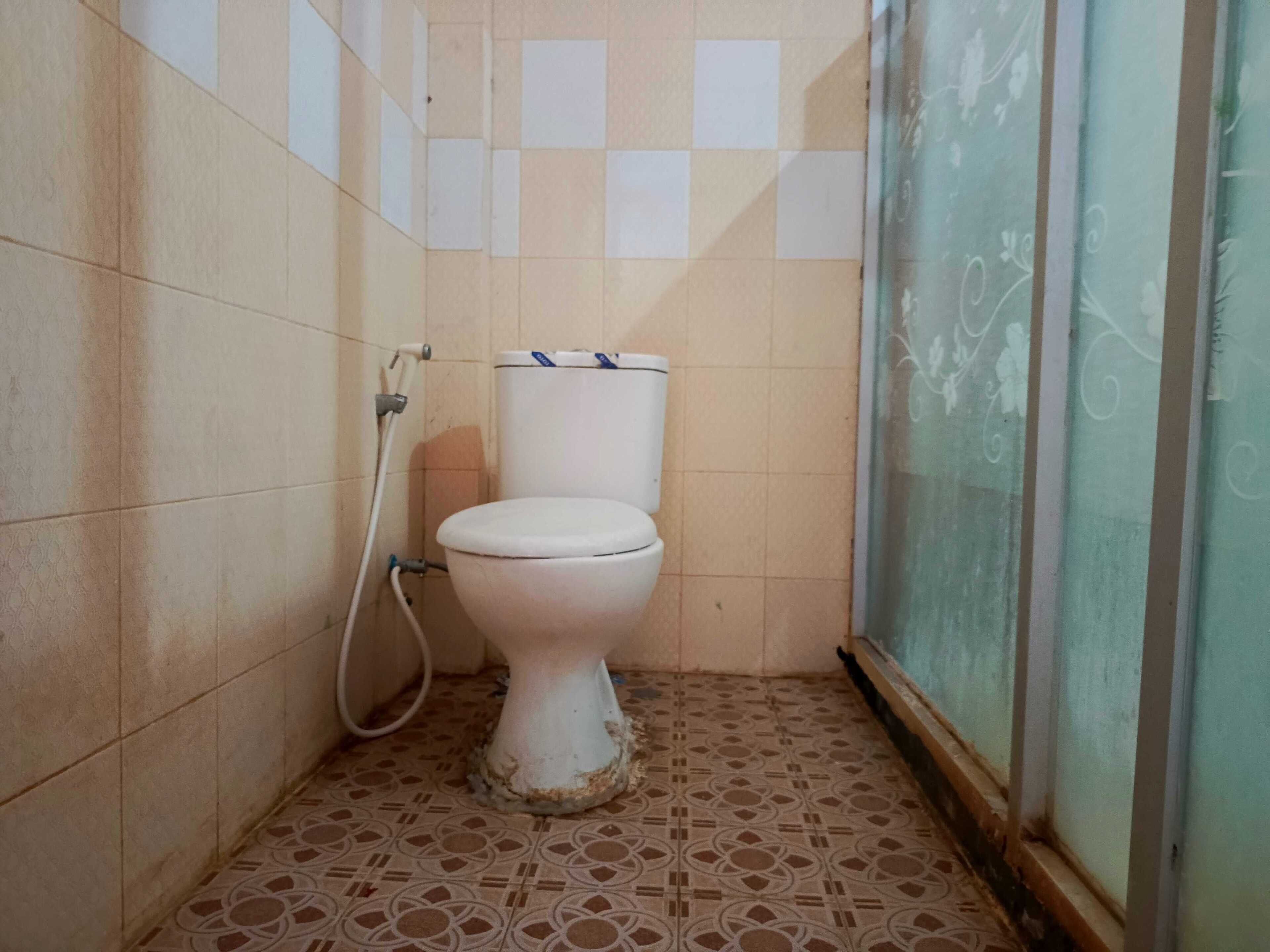 A small, tiled bathroom with a toilet, a shower, and a glass door.