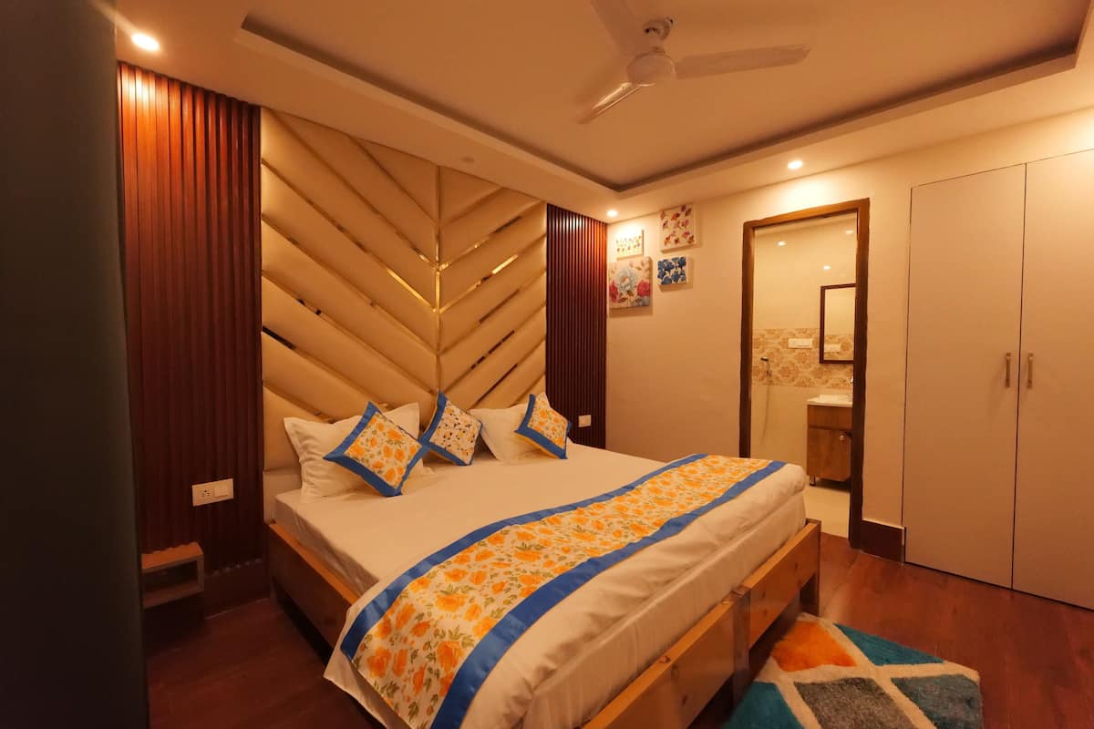 Un dormitorio con cama, cabecera de madera, mesitas de noche, armario y ventilador de techo.