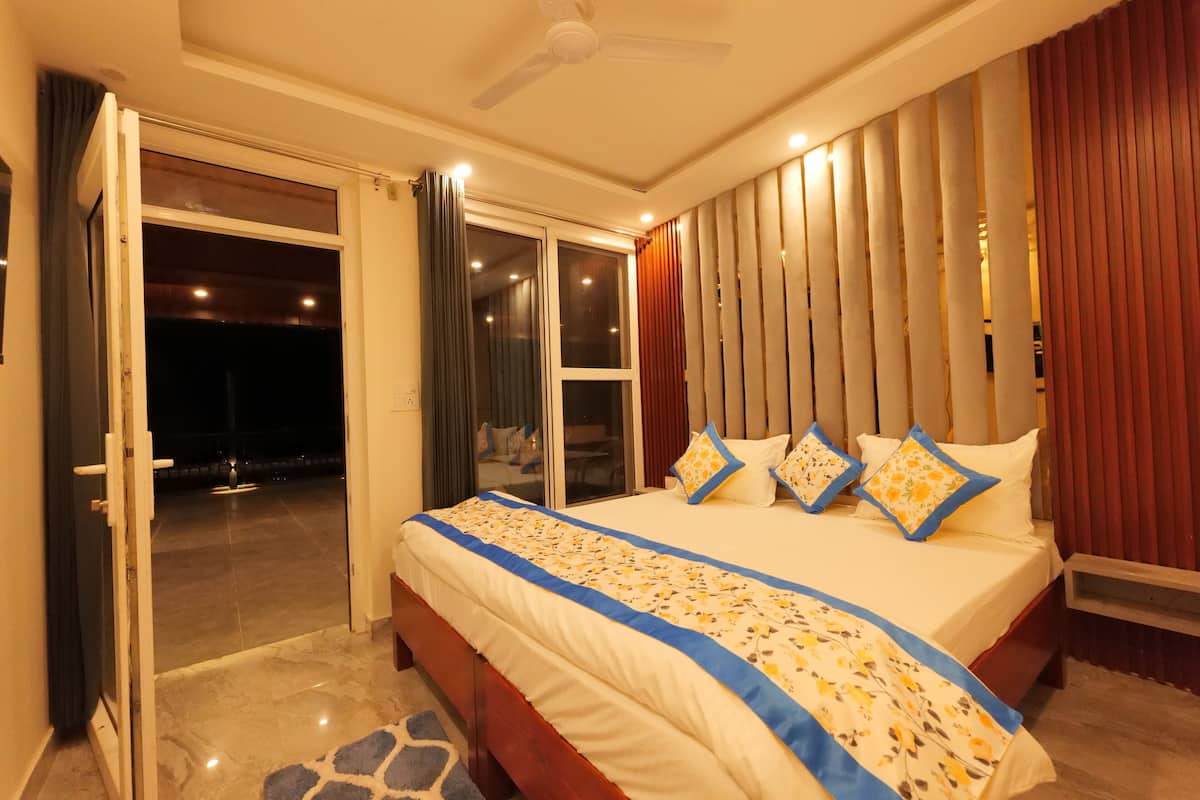 Un dormitorio con una cama grande, ventilador de techo y puerta corrediza de vidrio que da a un espacio exterior.