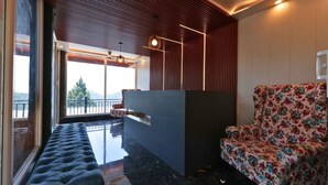 A modern interior with a sofa, a wooden accent wall, and a view to the outside. - Hotel Rex  (Dehradun)