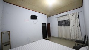 A room with a bed, a television mounted on the wall, a mirror, and a curtain. - Hotel O Kos Citra Syariah Near Bukit Marezo (Makassar)