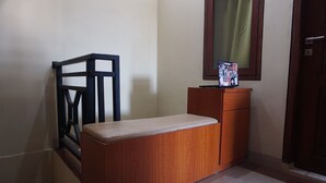 A corner of a room with a wooden bench, a small wooden cabinet, and a mirror on the wall. - Hotel O Kos Citra Syariah Near Bukit Marezo (Makassar)
