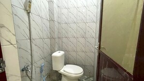 A small bathroom with a toilet, a shower, and a tiled floor. - Hotel O Kos Citra Syariah Near Bukit Marezo (Makassar)