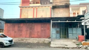A building with a red facade, a glass entrance, and a visible staircase leading to the entrance. - Hotel O Kos Citra Syariah Near Bukit Marezo (Makassar)
