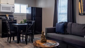 Een moderne keuken met een zwarte koelkast, witte kasten en een eethoek met zwarte stoelen en een houten tafel.