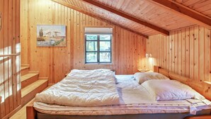 Une chambre dans une cabane en bois, avec un lit, une fenêtre et un tableau accroché au mur.