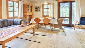 Un intérieur de chalet chaleureux avec un coin repas, un canapé et une table avec des chaises.