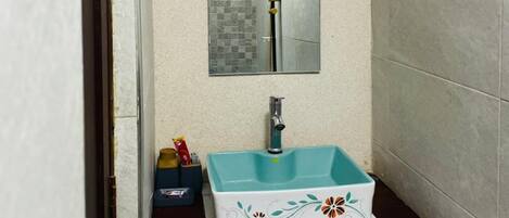 A bathroom with a white sink, a mirror, and a shower head.