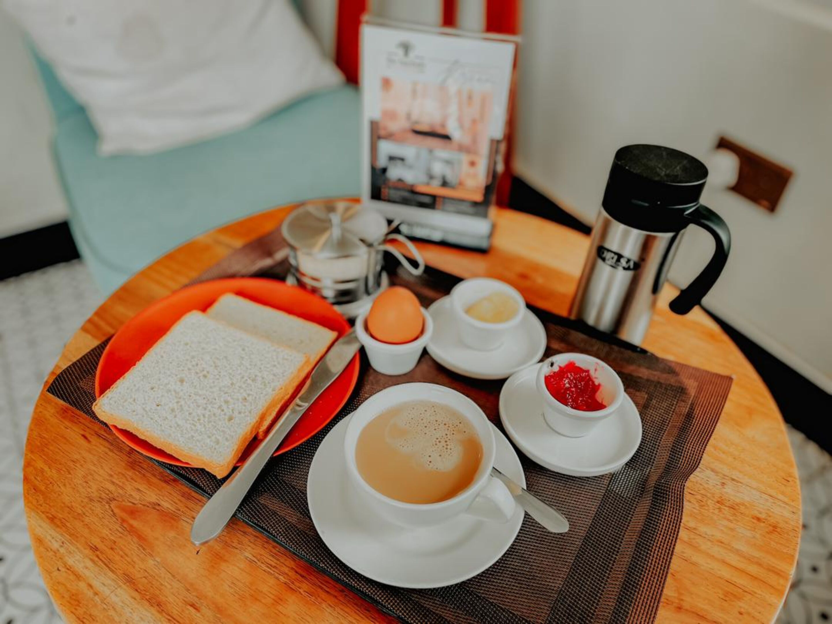 Un plateau de petit-déjeuner avec des toasts, du café et de la confiture, posé sur une table ronde.