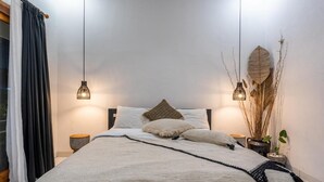 Un dormitorio moderno con una cama grande, dos mesitas de noche y un ventanal con cortinas.