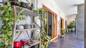 Un pasillo con un estante de madera que contiene utensilios de cocina y plantas en macetas.