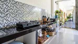 Una cocina con encimera negra, salpicadero de azulejos y diversos utensilios.