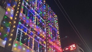 A building with multiple floors, adorned with colorful string lights. There is a sign for 'Shyam Palace' and another for 'Body Building Keep Fit Weight Loss'. - Hotel Shyam Palace (New Delhi)