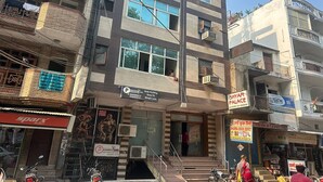A multi-story building with various commercial establishments on the ground floor, including a body building, a sports store, and a book depot. - Hotel Shyam Palace (New Delhi)