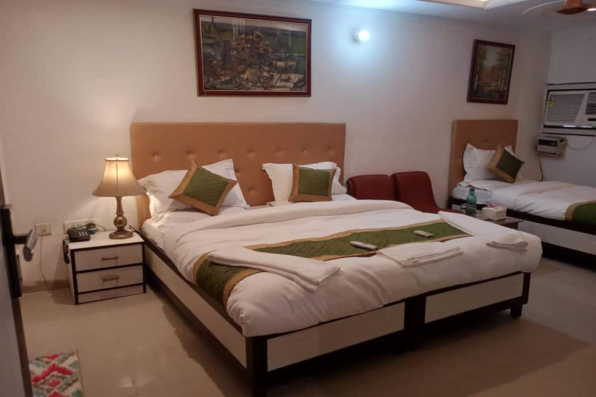 A hotel room with a large bed, bedside tables, a lamp, and artwork on the walls.