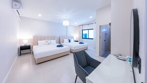 Une chambre d’hôtel moderne équipée de deux lits, d’un bureau, d’une chaise, d’une télévision et d’une porte de salle de bain.