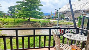 A balcony with a view of a river, greenery, and a distant building. - The Creek Resort (Doi Tao)