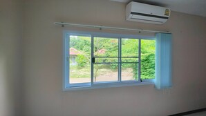 A room with a large window, an air conditioning unit, and a view of greenery outside. - The Creek Resort (Doi Tao)