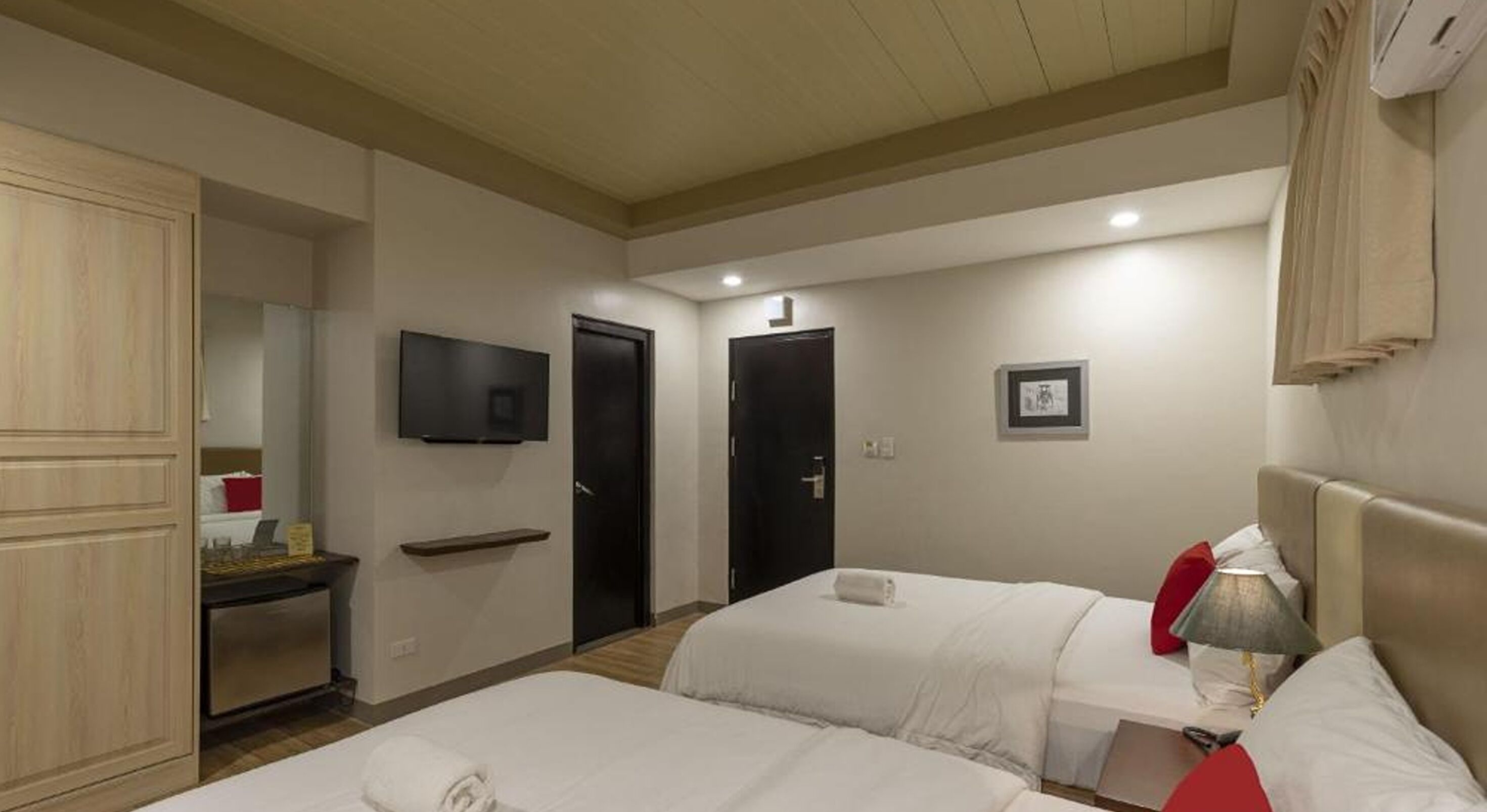 Habitación de hotel con dos camas, un televisor, un escritorio pequeño y un armario.