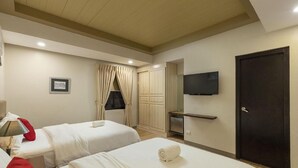 Une chambre d’hôtel avec deux lits, un téléviseur fixé au mur, une porte et un tableau encadré au mur.