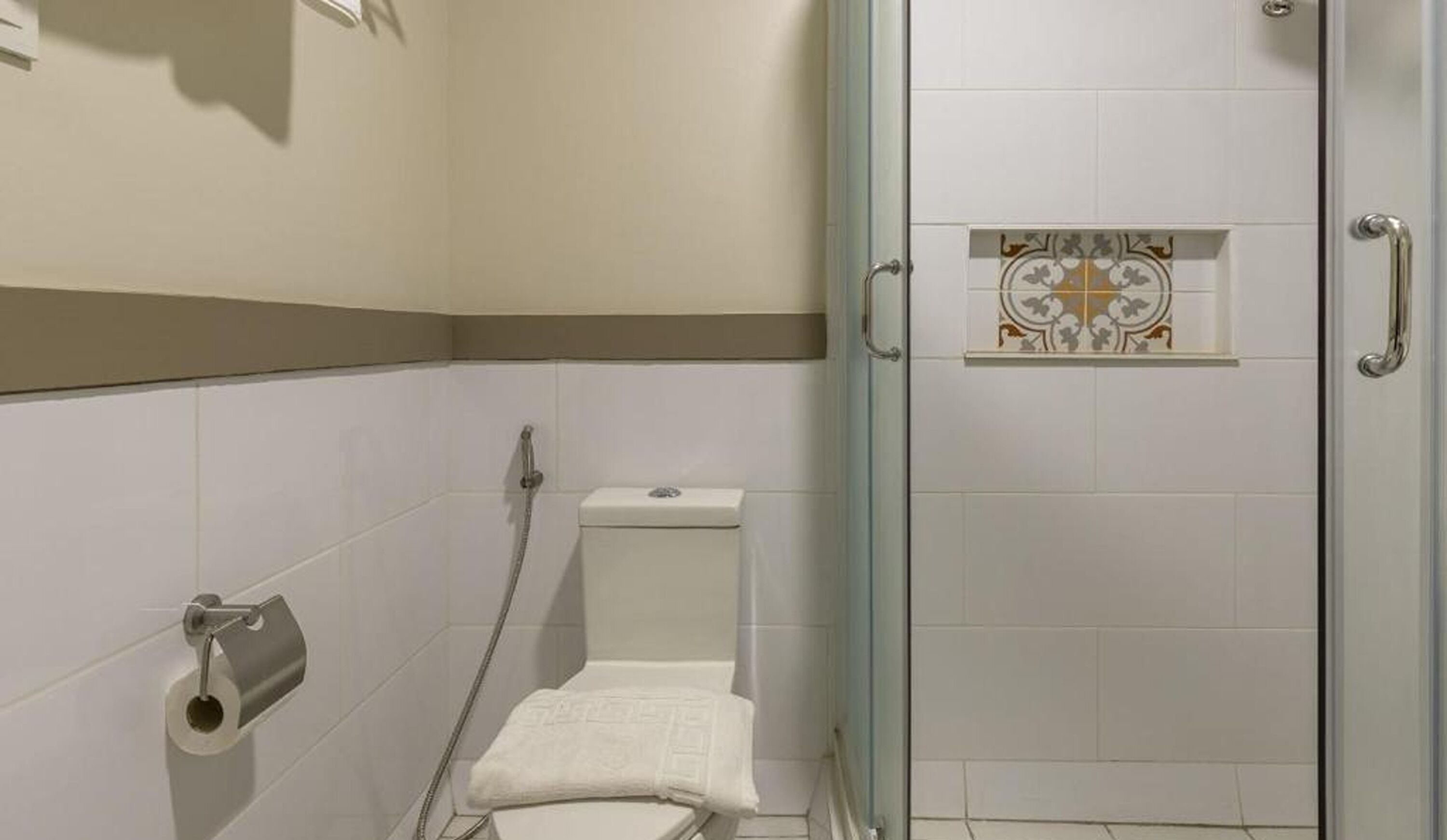Un espacio de ducha pequeño y cerrado, con un inodoro y un perchero para toallas.