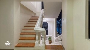 Un escalier avec des rampes blanches et des marches en bois menant à un balcon d’où l’on peut admirer le ciel nocturne.