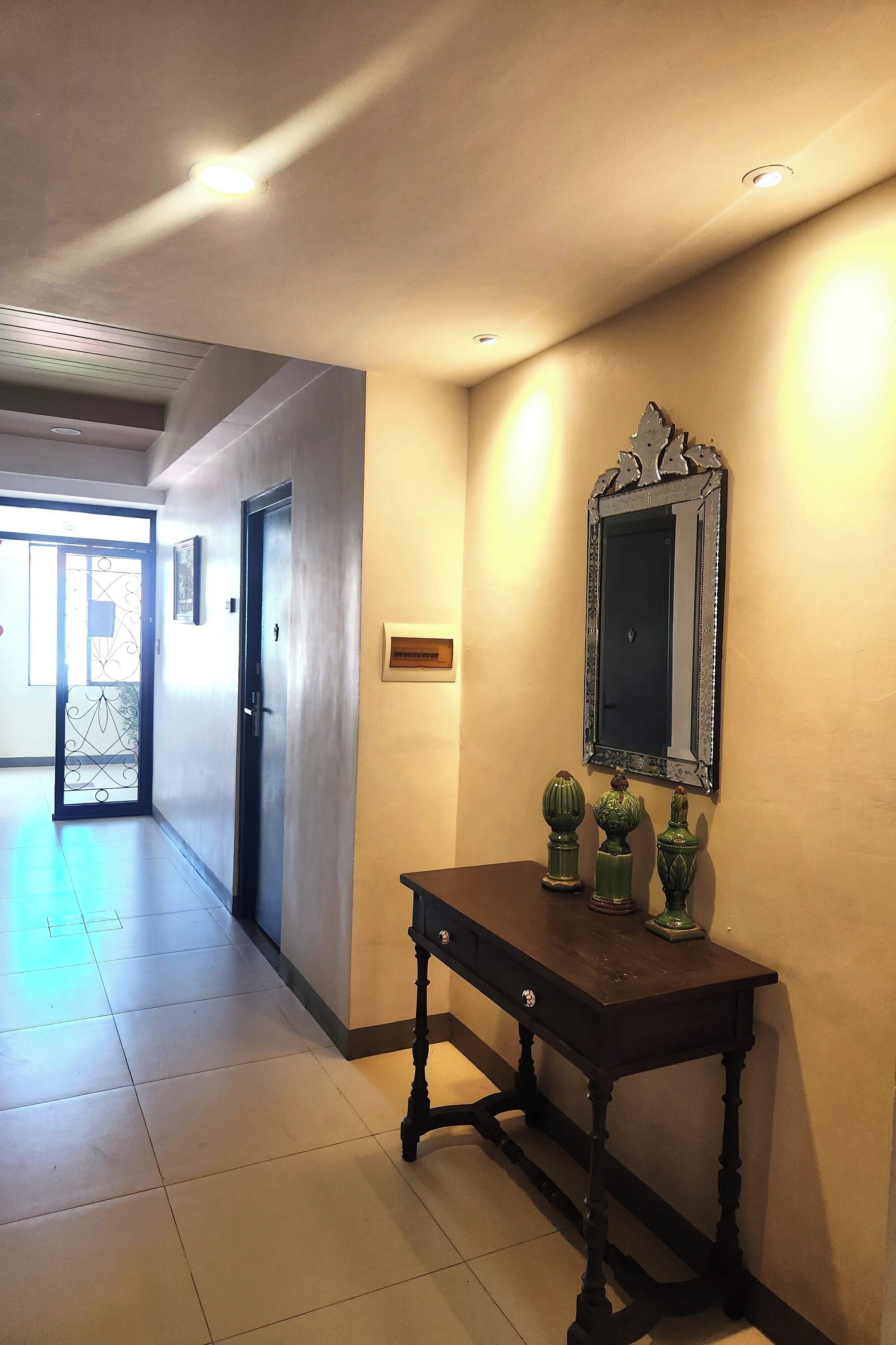 A hallway with a dark wooden table, a mirror, and decorative vases.