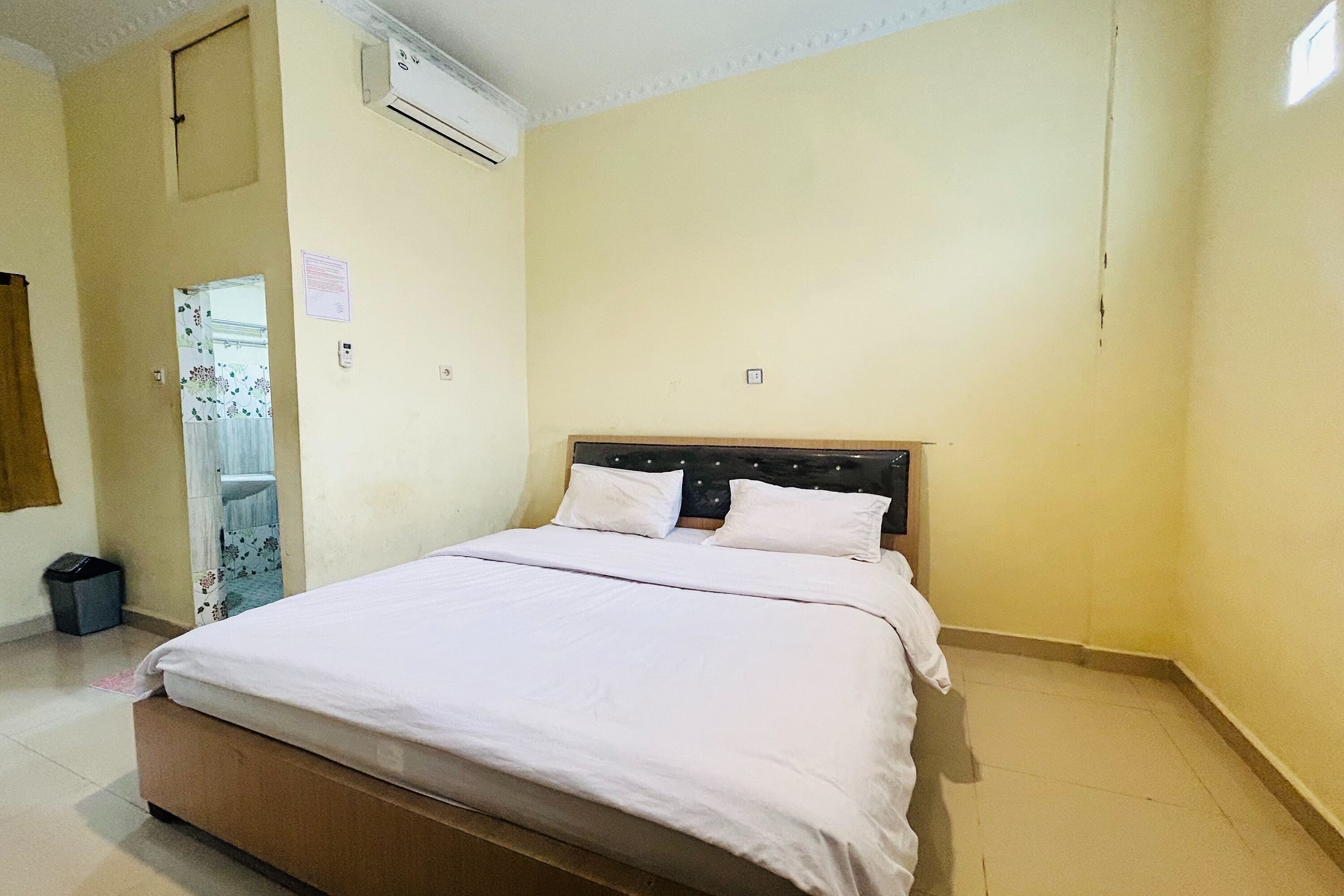 A bedroom with a bed, a wardrobe, and an air conditioning unit.