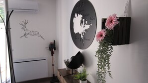 A room with a white radiator, a wooden cabinet, a wall-mounted light, a potted plant, and a decorative wall piece.