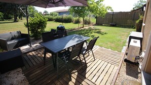 An outdoor patio with a table and chairs, a grill, and a covered area.