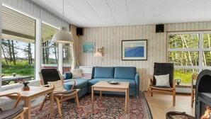 Una sala de estar acogedora con un sofá azul, sillas de madera, una mesa de centro y una chimenea.