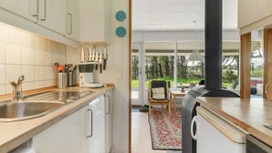 Una cocina moderna con armarios blancos, una estufa negra y vistas al exterior.