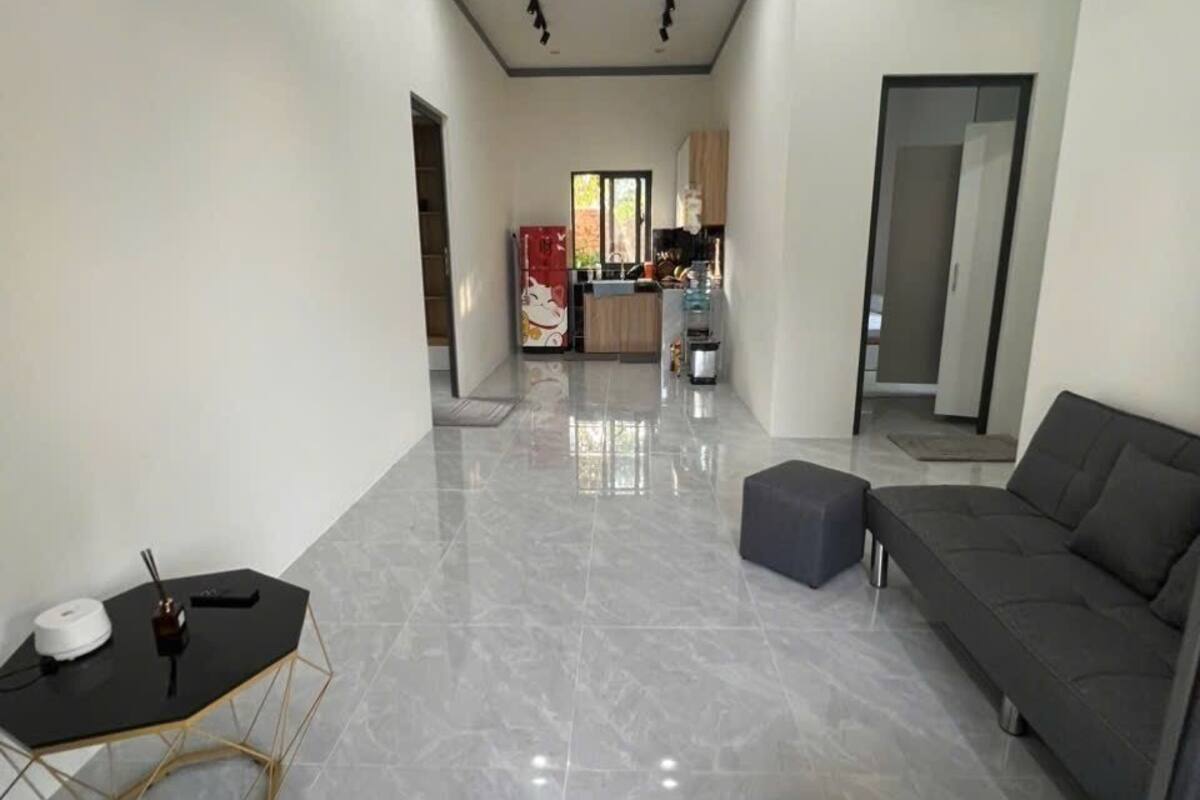 A spacious living area with a sofa, ottoman, and a hexagonal table.