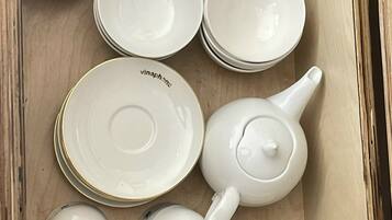 A wooden box containing various white ceramic dishes and teapots.