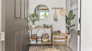 A hallway with a wooden bench, a small table, a mirror, and a welcome sign.