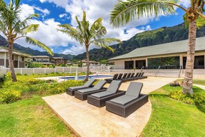 A poolside area with lounge chairs, a swimming pool, and a view of mountains.