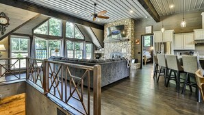 A spacious kitchen with a stone fireplace, wooden ceiling beams, and large windows. - Live Love Lake | Blue Ridge, GA (Blue Ridge)
