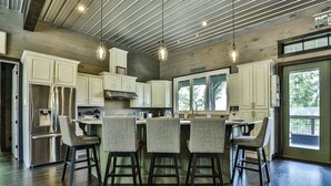 A modern kitchen with white cabinets, stainless steel appliances, and a central island with bar stools. - Live Love Lake | Blue Ridge, GA (Blue Ridge)
