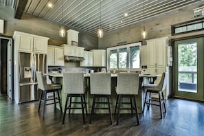 A modern kitchen with white cabinets, stainless steel appliances, and a central island with bar stools.