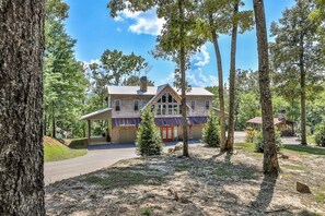 A two-story house with a covered porch, surrounded by trees.